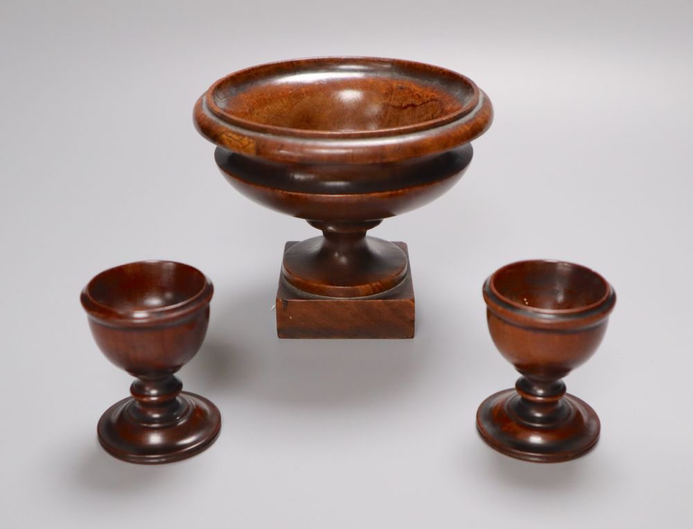 A 19th century turned amboyna urn, 11cm and two late Georgian turned mahogany egg cups, 6.5cm